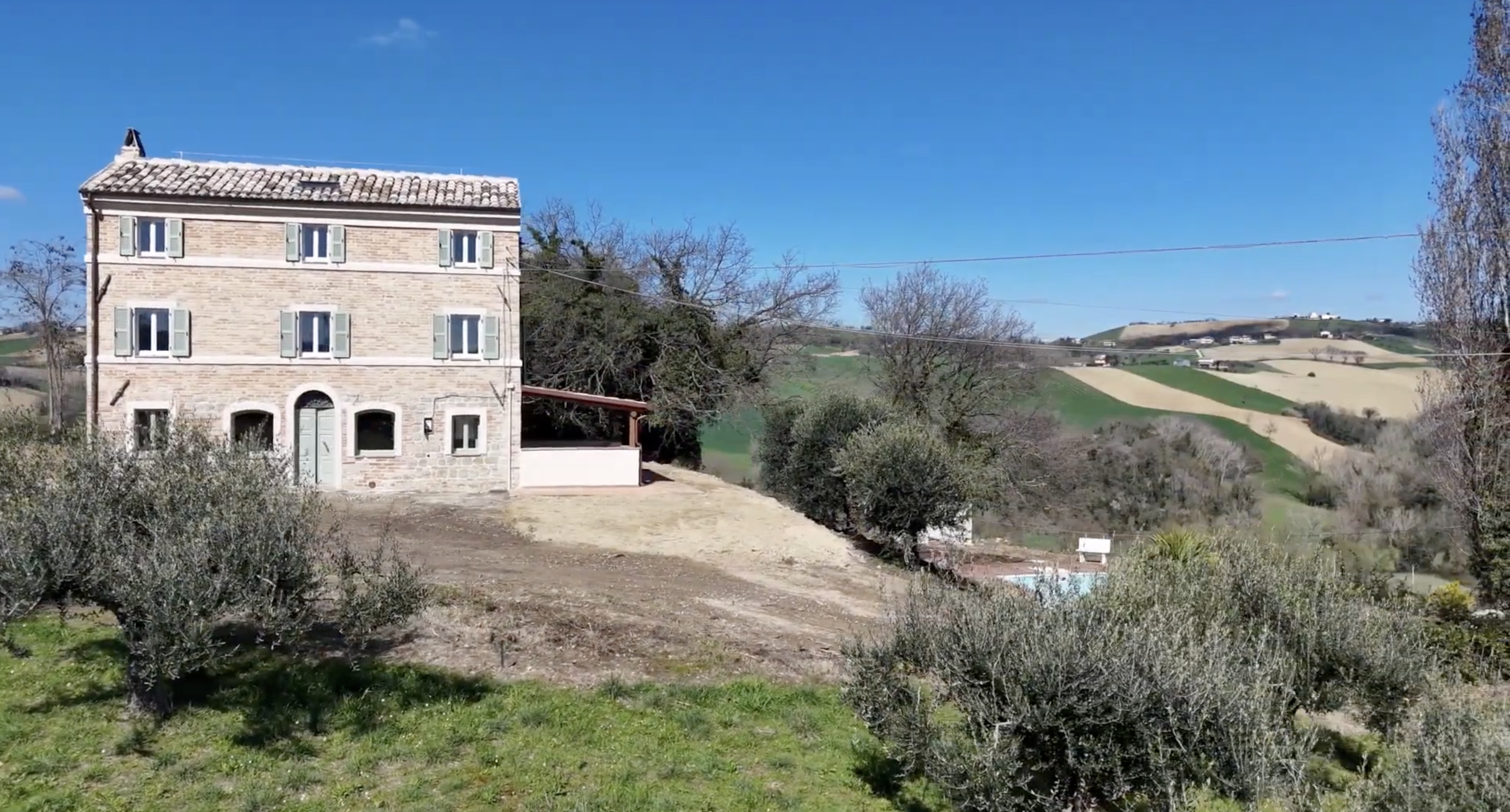The house on the hillside among olive trees, with the valley and hills beyond