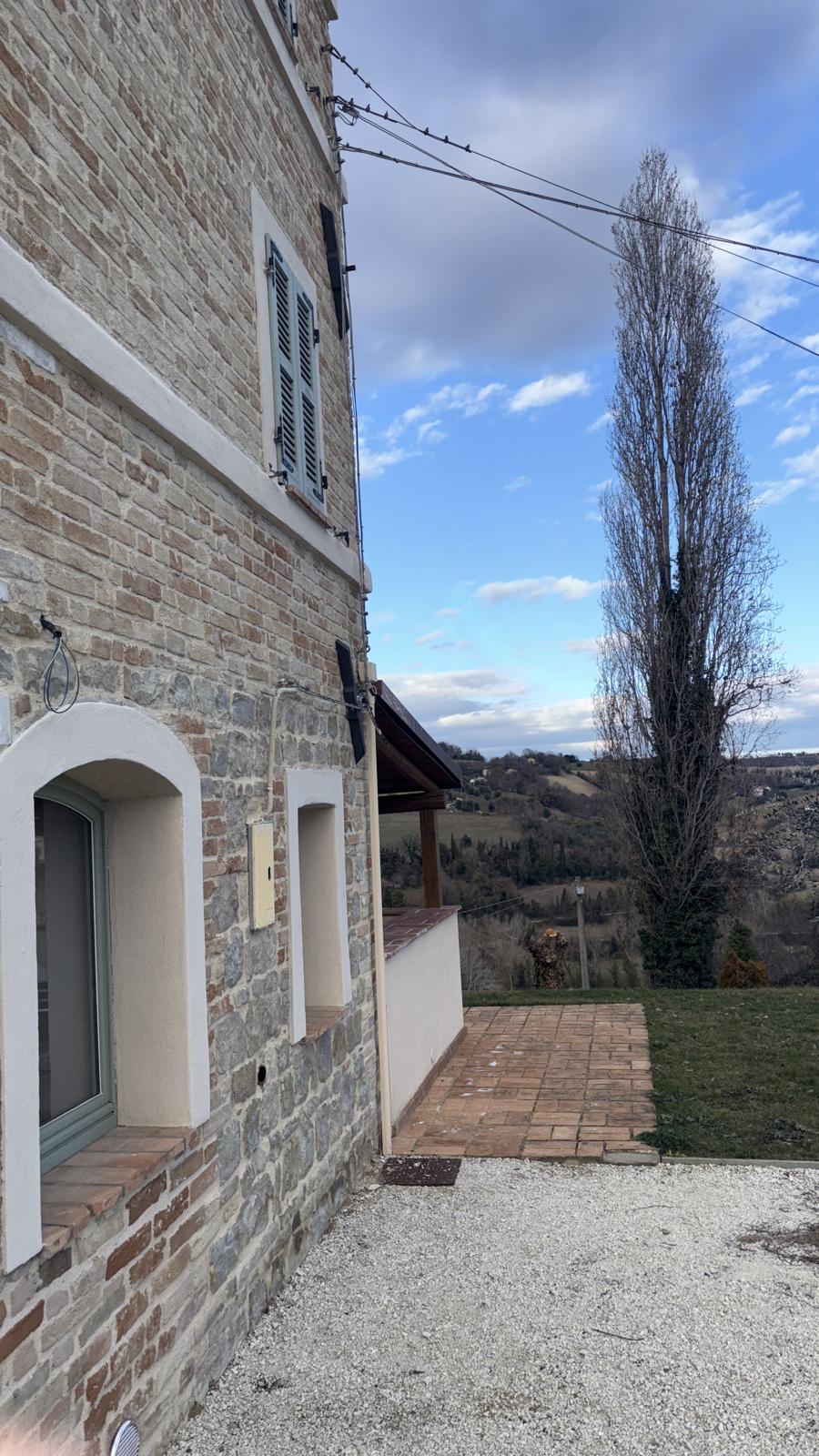 The stone side of the house, with the poplar and the valley beyond