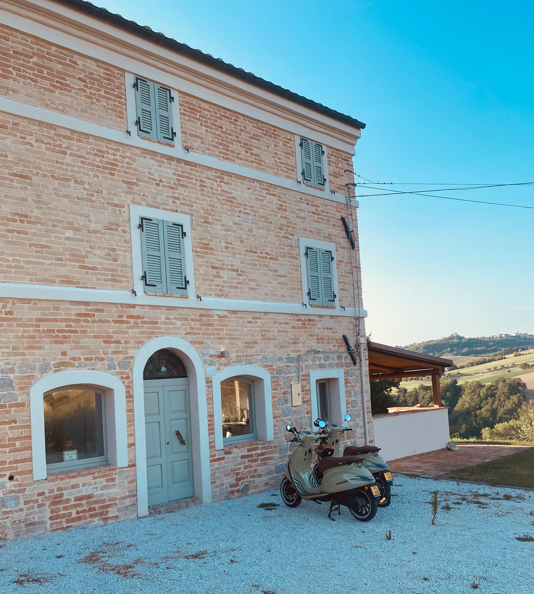 The front of the house with two scooters on the gravel
