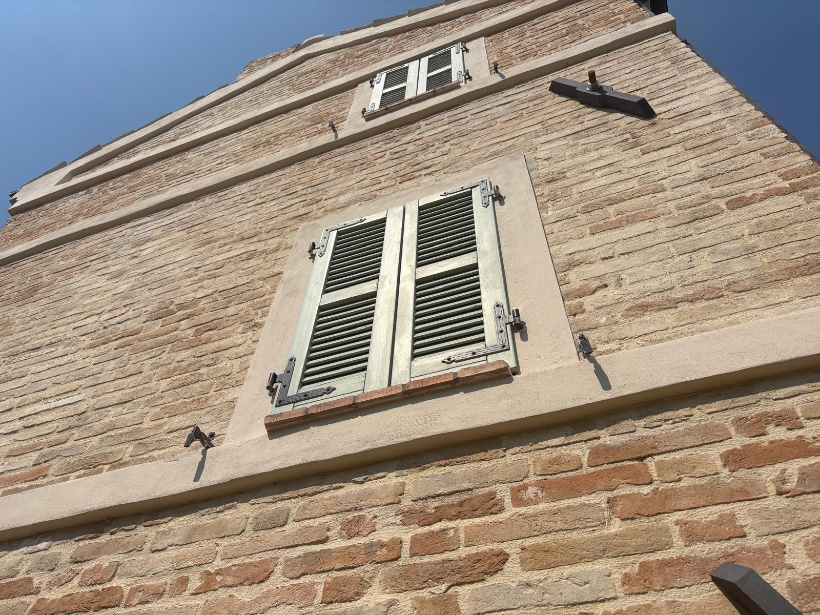 Restored green shutters seen looking up the brick facade