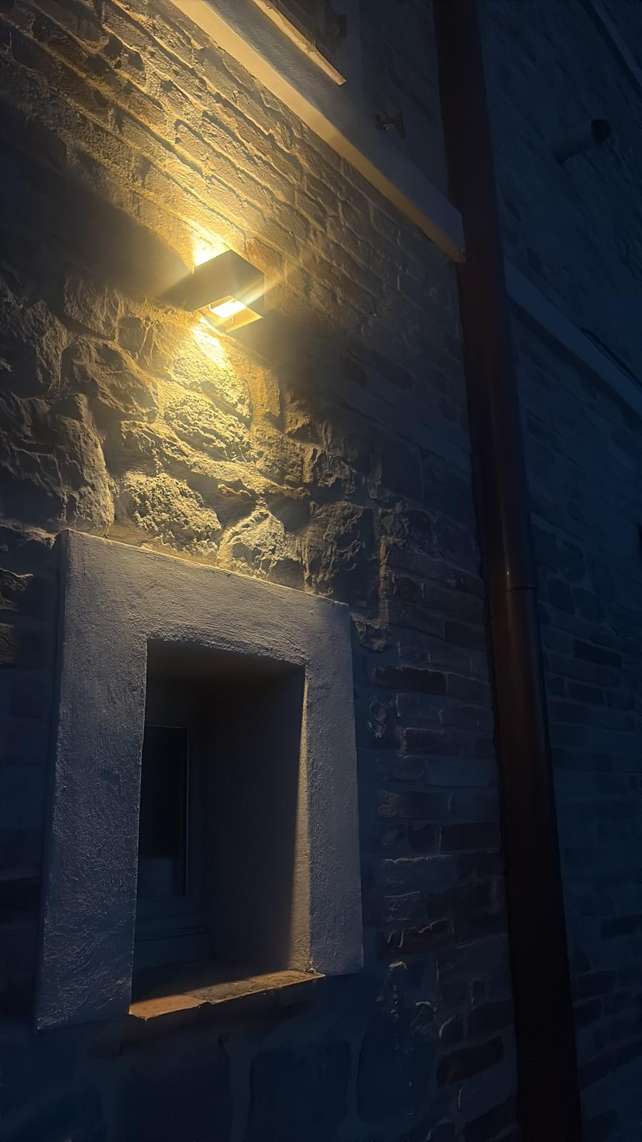 A wall light on the old stonework after dark