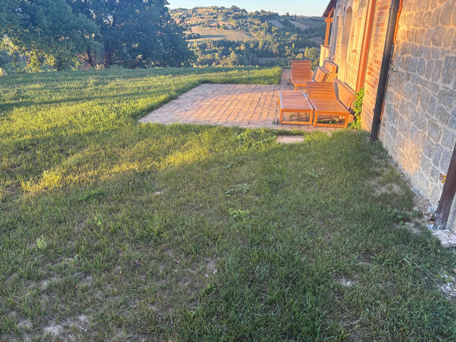 Loungers on the brick terrace beside the house in evening light